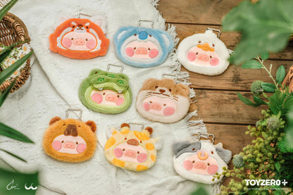 Set of cute Lulu the Piggy Animal Party plush pouch keychains on a wooden surface with plants around